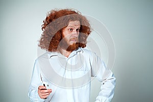 Portrait of puzzled man talking on the phone a gray background