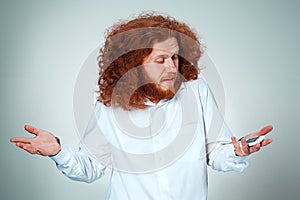 Portrait of puzzled man talking on the phone a gray background