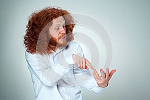 Portrait of puzzled man talking on the phone a gray background