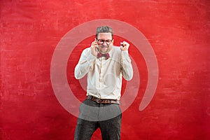 Portrait of puzzled man talking by phone a red background