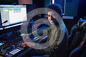 Portrait of radio host using sound mixer in studio