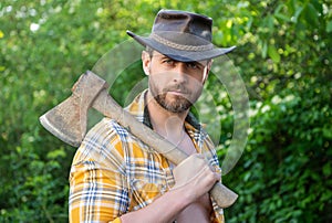portrait of rancher with axe wearing checkered shirt. rancher with axe outdoor