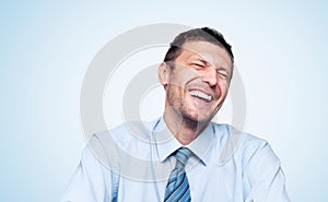 Portrait of a real happy laughing bearded man in a shirt with a tie on light blue background photo