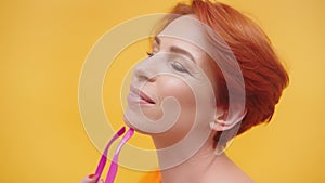 Portrait of red hair woman in her 40s isolated on yellow background.