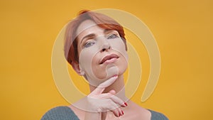 Portrait of red hair woman in her 40s isolated on yellow background.