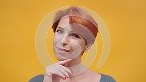 Portrait of red hair woman in her 40s isolated on yellow background.
