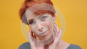 Portrait of red hair woman in her 40s isolated on yellow background.