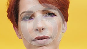 Portrait of red hair woman in her 40s isolated on yellow background.