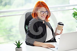 Portrait red-haired beautiful woman working in the office.