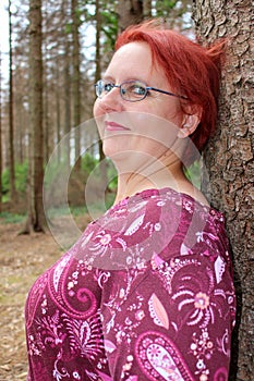 Portrait of a red-haired cheerful woman in the forest on a beautiful sunny summer day photo