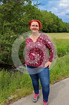 Portrait of a red-haired cheerful woman by a small creek on a beautiful sunny summer day in Menden Sauerland photo