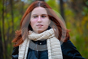 Portrait of a red - haired smiling girl in a jacket smiling . against the background of autumn nature, the concept of human