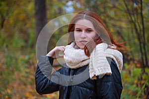 Portrait of a red - haired smiling girl in a jacket smiling . against the background of autumn nature, the concept of human