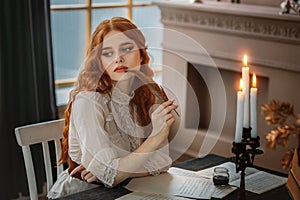Portrait red-haired vintage woman writer holding bird feather in hands. Medieval girl sit at table writes book, letters