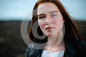 Portrait of a red-haired woman with freckles, illuminated by the sun.