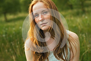Portrait of redhead girl. Summertime. Blossom meadow