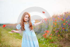 Portrait redhead little child with two wild flowers at hands sta