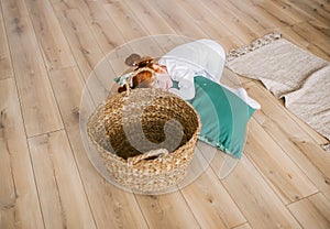 Portrait of redhead little girl in pajamas with bif basket in home interior