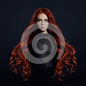 Portrait of redhead woman with long hair on black backgroun photo