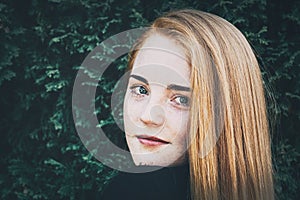 Portrait of a redhead woman with green pine leaves in the background artistic conversion