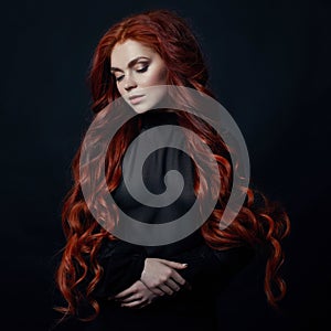 Portrait of redhead woman with long hair on black backgroun