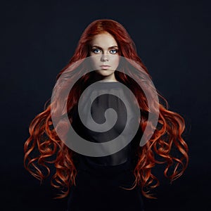 Portrait of redhead woman with long hair on black backgroun