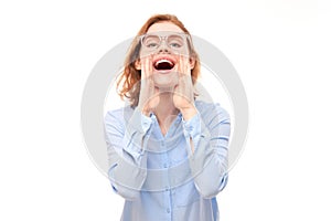 Portrait of redhead young woman screaming into her palms on white studio background. Important information