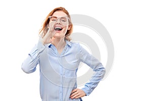 Portrait of redhead young woman screaming into her palms on white studio background. Important information