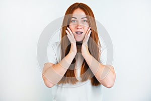 Portrait of redheaded young woman looking natural standing on isolated white backgroung touching her face surprisingly, body