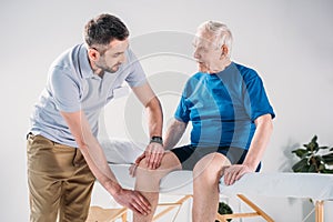 portrait of rehabilitation therapist doing massage to senior man