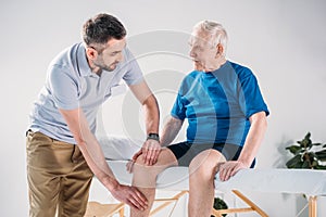 portrait of rehabilitation therapist doing massage to senior man photo
