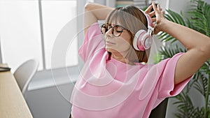 Portrait of a relaxed beautiful hispanic woman business worker listening to music on her smartphone, while resting her hands on