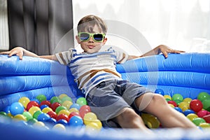 Portrait of relaxed boy in an inflatable ball pool