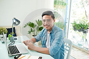 Portrait of a relaxed casual young asian business man with compu