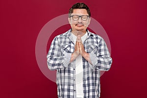 Portrait of relaxed handsome middle aged business man in casual checkered shirt and eyeglasses standing with palm hands and doing