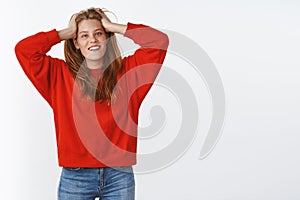 Portrait of relaxed outgoing good-looking young white female in stylish red sweater holding hands on head carefree