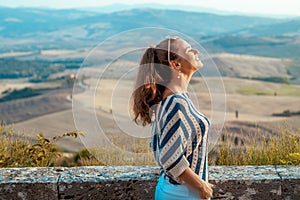 Relaxed stylish traveller woman in front of scenery of Tuscany