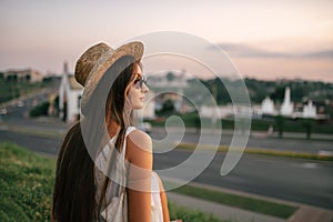 Portrait of a relaxed woman with hat looking forward at the horizon cityscape in the background copy space