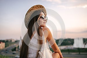 Portrait of a relaxed woman with hat looking forward at the horizon cityscape in the background copy space