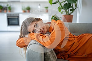 Portrait of relaxed woman lying on sofa with head bowed on armrest look at camera with calm emotion.