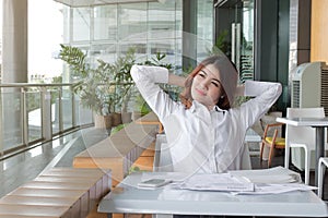 Portrait of relaxed young Asian business woman looking at far away in office.