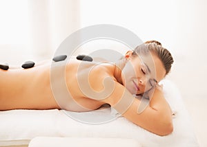 Portrait of relaxed young woman receiving hot stone massage