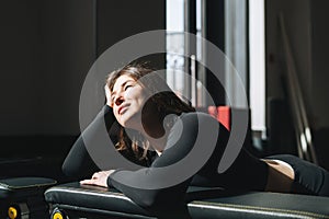 Portrait of resting young brunette woman in sport active wear in fitness club gym