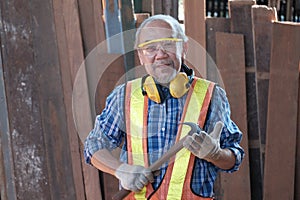 Portrait of retired Asian old man who came to work as carpenter, holding hammer with happiness and smile. By occupation in the