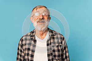 Portrait retired old man with white hair and beard laughter excited over blue color background