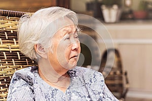 Portrait of a retired old woman seated with a concerned or sad e