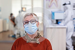 Portrait of retired patient in dental office looking on camera wearing face mask