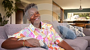 Portrait Of Retired Smiling Senior Woman Relaxing On Sofa At Home