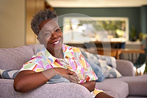 Portrait Of Retired Smiling Senior Woman Relaxing On Sofa At Home