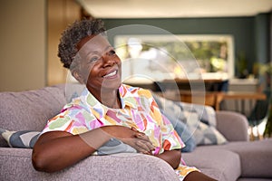 Portrait Of Retired Smiling Senior Woman Relaxing On Sofa At Home